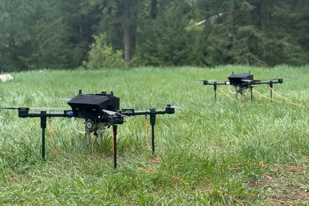 Two Rosor Recon Lite drones staged in a grassy clearing on the Gull River program, tow cables laid out behind them